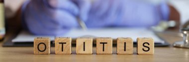Sıraya dizilmiş tahta küplerden yapılmış otitis kelimesine yakın çekim. Doktor otolaryngolog reçete yazıyor. Kulak iltihabının teşhisi ve tedavisi