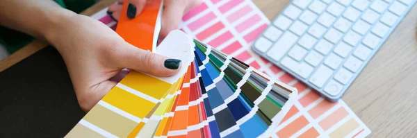 Close-up of interior designer holding fan of multicolored samples. Woman searching proper colour for further promotion. Design concept