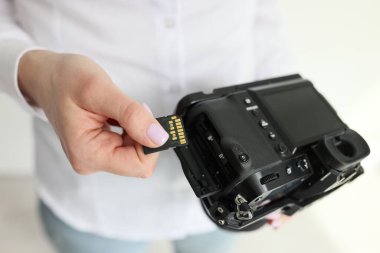 Kadın kameraman, ışık odasında duran kameraya bilgi depolama aygıtı yerleştiriyor. Genç kadın profesyonel atış için ekipman hazırlıyor.