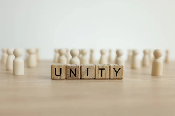 Słowo Jedność Wykonana Drewnianych Kostek Przeciwko Białym Postaciom Symbolizującym Jedność — Zdjęcie stockowe