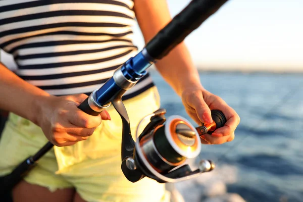 縞模様のTシャツの男は魚を捕まえる 漁師は釣竿を持ち リールを回転させて魚をルアーさせる 日没時に川の近くで自然を楽しむ — ストック写真