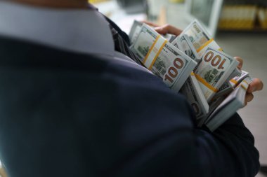 Başarılı menajer, sayılan para yığınlarını elinde tutuyor. Takım elbiseli adam müşteriyle başarılı bir emlak anlaşmasından büyük kar elde ediyor.