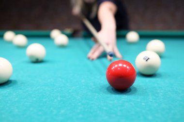 Kadın oyuncu kırmızı topa mavi bilardo masasında vurmaya hazır. Aktif kadın hafta sonları bilardo oynamaktan hoşlanıyor. Eğlence hobisi ve para kazanma kavramı