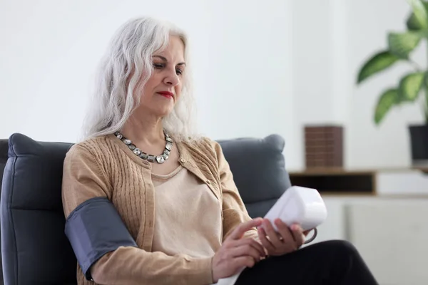 Senior Vrouw Gebruikt Digitale Tonometer Bloeddruk Meten Zittend Een Fauteuil — Stockfoto