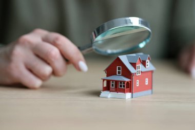 Kadın, konağın küçük modelinin üzerinde büyüteç taşıyor. Kadın emlakçı emlak durumunu kontrol ediyor. Mülk inşaatının ayrıntılı incelemesi