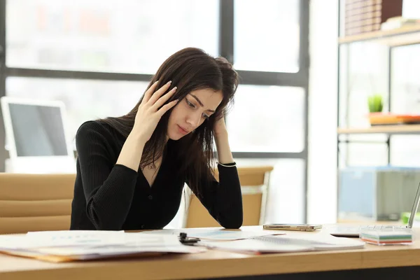 関係者の女性は手で頭を保持する困難なプロジェクトを考えています 現代オフィスのテーブルに座って仕事のための若い管理者の懸念 — ストック写真