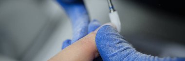 Close-up of manicurist in gloves doing hardware manicure to client using special apparatus. Beauty day and body care concept