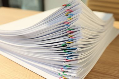 Ofisteki ahşap masaya iğnelerle tutturulmuş kağıtlar. İş yerinde muhasebe bilgilerini içeren belgeler değerlendirmeye hazır