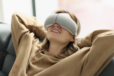 Rahat kadın özel gözlük takarak göz masajından hoşlanır. Mutlu ev hanımı evde rahat bir kanepenin arkasına yaslanmış gülümsüyor.