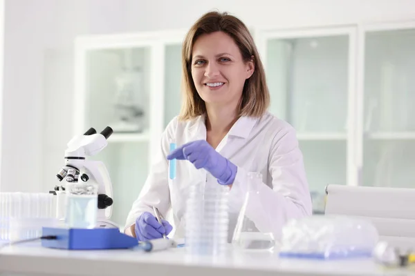 Mutlu Bayan Laboratuvar Çalışanı Mavi Sıvıyla Tüpü Mikroskop Altında Incelemeye — Stok fotoğraf
