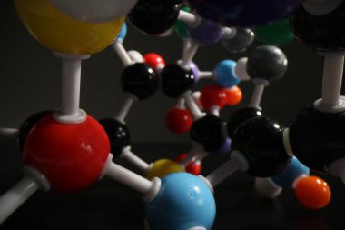 Koyu arkaplandaki moleküler bileşiklerin gerçekçi modeli. Renkli moleküllerin süreçlerini ve bağlantılarını temsil eden atomik sistem