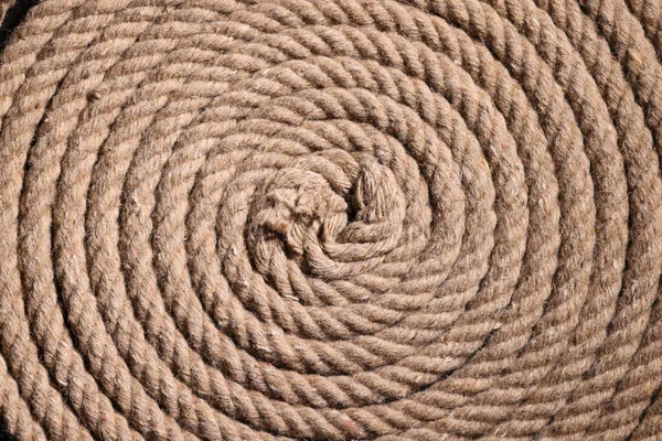 Coil of twisted strong brown rope as background texture. Old vintage sailboat rope ready for use. Tool made of weathered hemp material