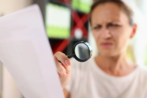 stock image Portrait of woman trying read papers with magnifier glass, squinting to see more clearly. Female having difficulties seeing text because of vision problems