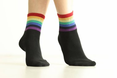 Beyaz arka planda LGBTQ bayrak dekoru olan siyah çorap giyen biri. Hassas sosyal grupları desteklemek için günlük aksesuar