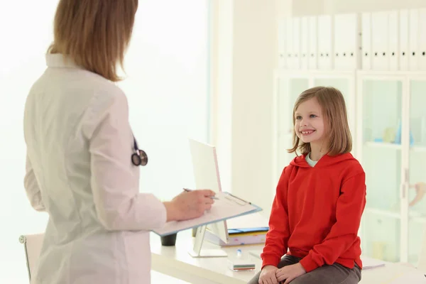 クリップボードを持つ女性医師は 入院中に肯定的な女の子を調べます 女性小児科医インタビュー患者 子供のための近代的な医療 — ストック写真