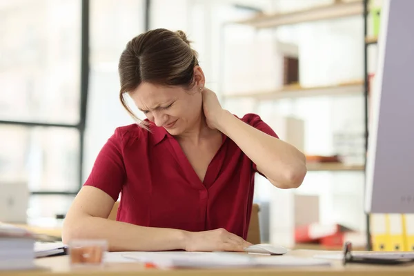 女性マネージャーは会社の職場の机に座って首を痛めています 女性従業員の健康への過労の影響 — ストック写真
