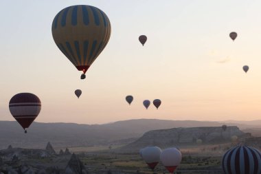 Kapadokya 'nın parlak gündoğumunda havada yüzen renkli sıcak hava balonları. Sabahın erken saatlerinde manzara ve turistik eğlence.