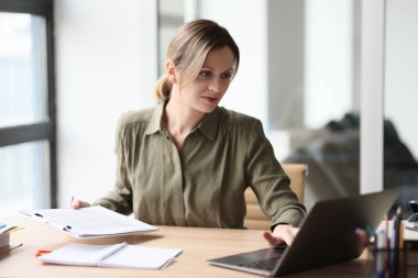 Üzerinde proje materyalleri olan bir klavyeye odaklanmış bir kadın. Sarışın bayan yönetici, ofisteki ahşap masada anlaşma yapmaya çalışıyor.