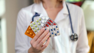 Beslenme uzmanının elinde klinikte su toplayan farklı haplardan var. Tıbbi üniforma uzmanı sağlıklı vücut için besin takviyesi öneriyor.