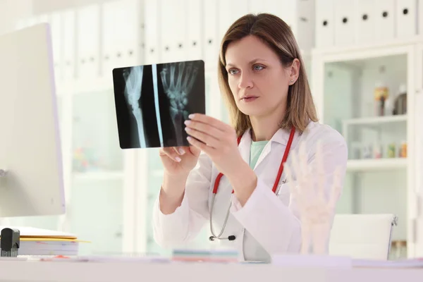 女医生在临床前提下研究病人手臂坐在桌旁的X光照片 创伤专家控制受伤后的康复过程 治疗和保健概念 — 图库照片
