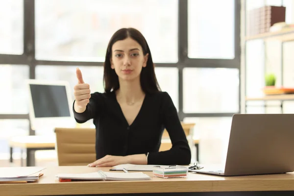 成功した女性マネージャーは承認サインがテーブルに座って表示されます ブルネットの従業員は 会社のオフィスで親指アップで労働条件を承認します — ストック写真
