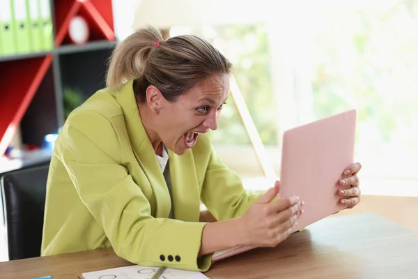 女性はオフィスのテーブルに座って喜んでノートパソコンの画面を見て叫ぶ 起業家は感情的に反応するビジネス開発に関する良いニュースを受け取る — ストック写真