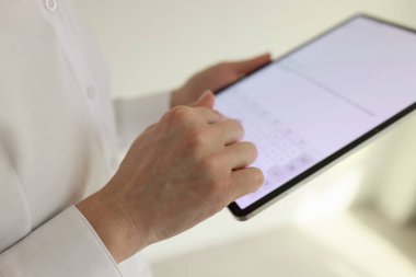 Tabletteki meslektaşına mesaj yazan kadın yöneticinin eli. Kadın, ofisteki müşterilerle iletişim kurmak için modern elektronik cihaz kullanıyor.