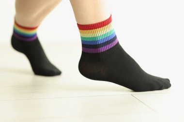 Döşeme üzerinde LGBTQ bayrağı olan çorap giyen biri. Gökkuşağı kenarlı moda aksesuarları. Cinsel azınlık desteği gösterisi