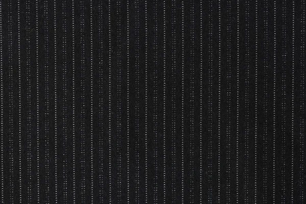 Black pinstripe suit fabric with tiny white dots used for clothing manufacturing. Quality textile material texture as background. Catalog photo sample