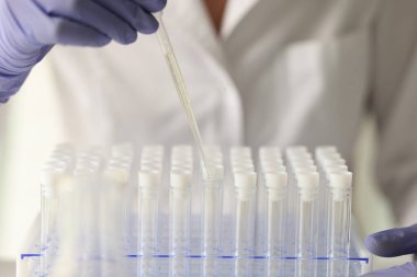 Laboratuvar asistanı test tüplerindeki sıvılarla çalışıyor. Bilim adamı şeffaf sıvıyı inceliyor. İnsan sağlığını iyileştirmek için kimyasal maddelerin özellikleri araştırılmaktadır