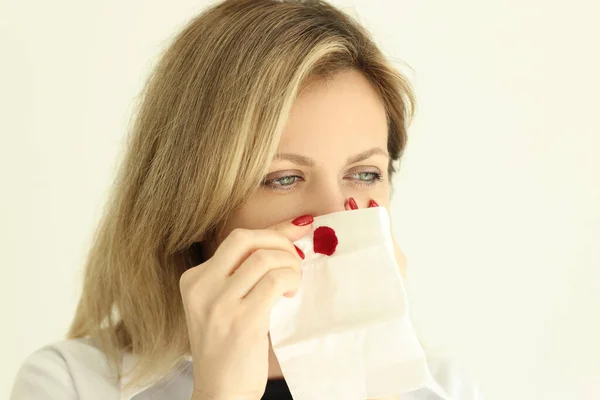 若い女性は ナプキンが出血を停止して鼻を拭く 病気ブロンドの女性は 粘膜の高血圧や損傷に苦しんでいます — ストック写真