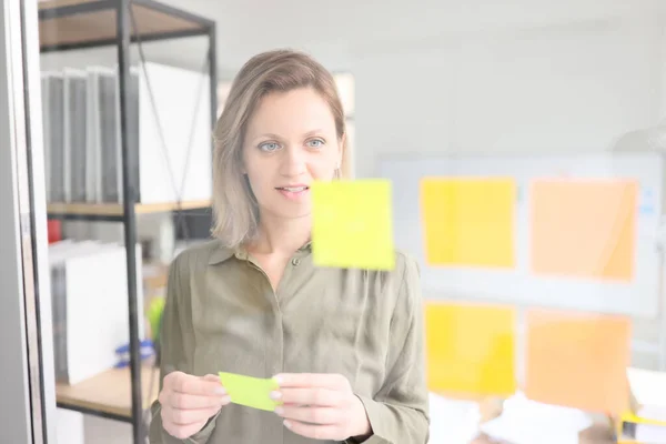 Geschäftsfrau Steht Glaswand Mit Memo Aufklebern Firmenbüro Mitarbeiter Hinterlässt Aufkleber — Stockfoto