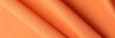 Top view of bright orange silk cotton fabric texture background. Bright orange wavy cloth backdrop for design art work