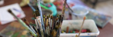 Top view of paint brushes in glasses at artist workplace. Art, teaching painting and drawing classes concept