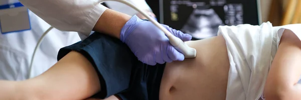 Close-up of doctor making examining with ultrasound of internal organs of child in clinic office. Ultrasound of abdominal cavity procedure concept