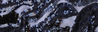 Close-up of black transparent fabric decorated with sequin flowers print textured background. Stylish material for sewing, decor and art work