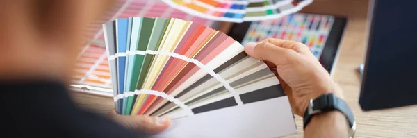 Hands of designers during the discussion and selection of colors for interior in studio. Designer communicates with client and selects color and shades in color palette