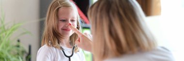 Steteskoplu doktor kızı ziyaret eden çocuklar pediyatrist ile iletişim kuruyor. Doktor, çocuğu olan bir hastayla konuşuyor ve hastalık önleme sağlık sigortası konusunda danışmanlık yapıyor.