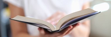 Kadın kitap okuyor ve sayfaları yakından inceliyor. Okuma ve eğitim aşkı
