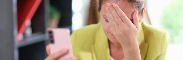 悲しい女の子は テーブルのオフィスでスマートフォンのモバイルメッセージで悪いニュースを読んで動揺しました おしゃべりと悪いニュース — ストック写真