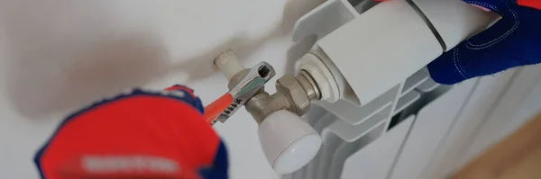 Close-up of man plumber installing heating radiator in apartment or house. Builder installs hot water central heating system. Repair concept