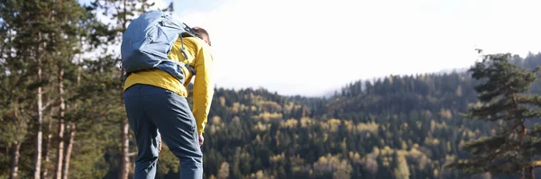 stock image Tired male traveler with heavy backpack bending over near forest lake back view. Hiking concept