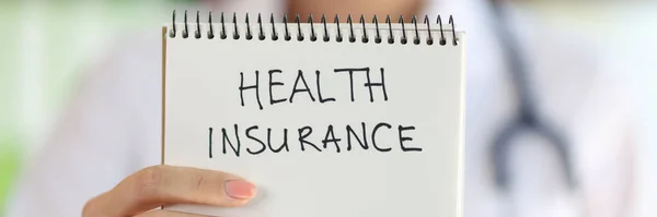 健康保険のレタリングと女性の手保持ノートパッドのクローズアップ 民間医療保険又は政策の考え方 — ストック写真