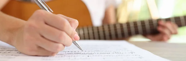 Zbliżenie Kompozytorki Piszącej Nuty Notatniku Muzyk Komponuje Muzykę Siedząc Gitarą — Zdjęcie stockowe