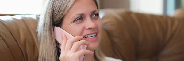 ソファに座りながら携帯電話で話している笑顔の女性 スマートフォンを持つ幸せな女性のクローズアップ — ストック写真