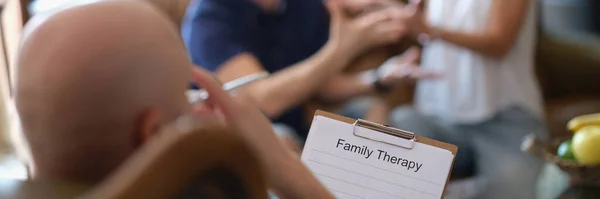 Clipboard with text family therapy and blurred married couple and psychologist. Solving family problems and psychological counseling.