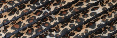 Stipes of fabric with leopard pattern close up. Brown spotted striped textile.