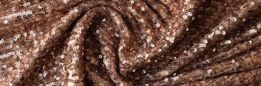 Brown textile decorated by plastic as background. Wavy fabric with shiny decoration close up.