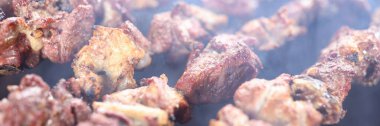 Cooking of shish kebab bbq on open fire. Meat skewers in smoke close up, barbecue picnic.