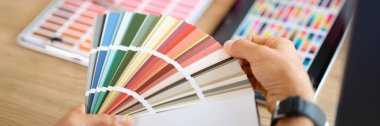 İki tasarımcı yeni projelerin renkleri hakkında tartışan birçok renk örneğine bakıyor. Renkli pantonlarla ve menajerlerle sanat stüdyosunda çalışma masası.